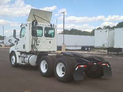 Truck chassis showing rear view with dual rear axles and exposed fifth wheel area under open cab on a Freightliner Cascadia daycab.