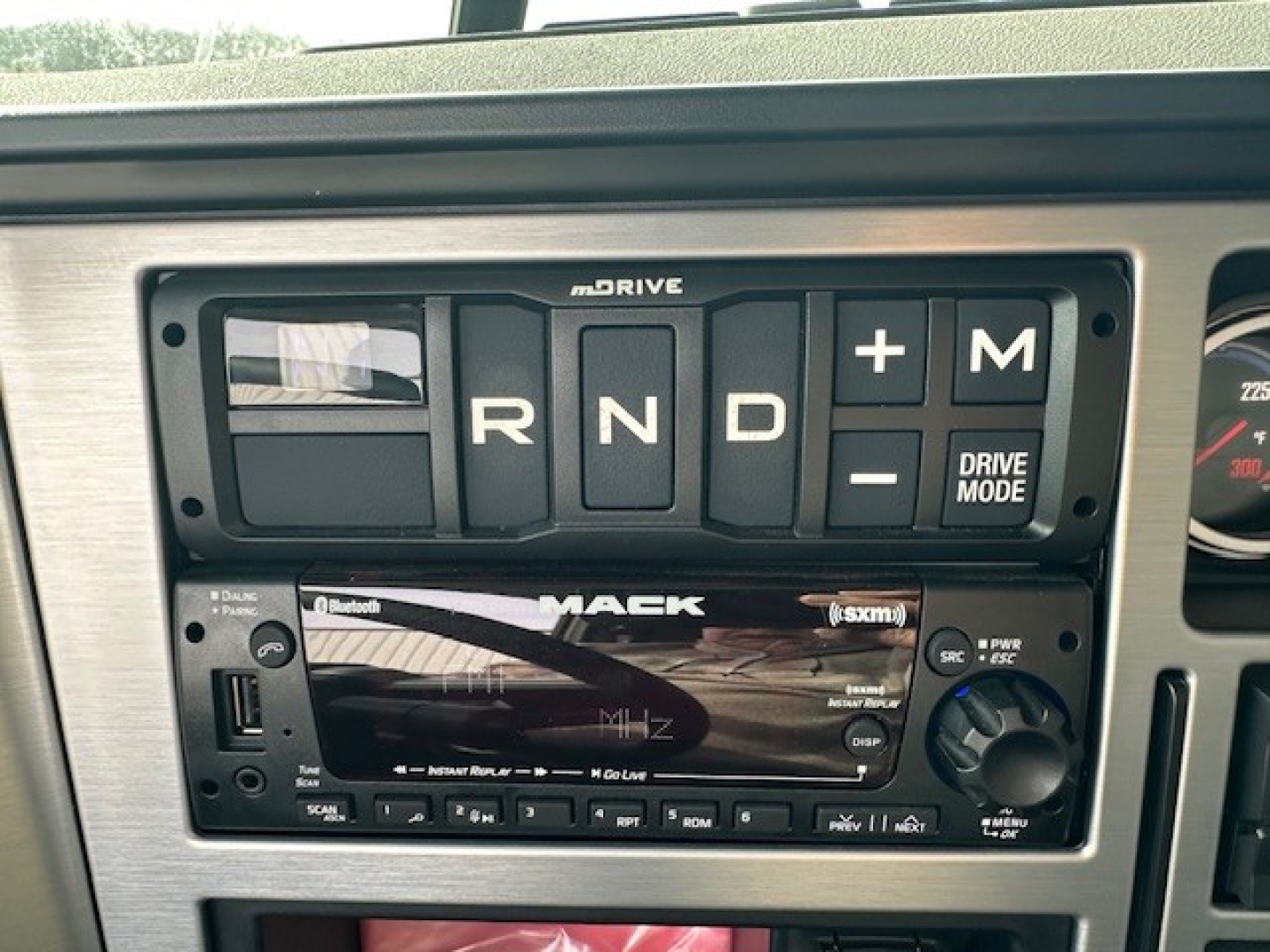 Mack GR104F dash with mDrive shifter and radio display showing R N D and plus/minusDrive Mode controls.