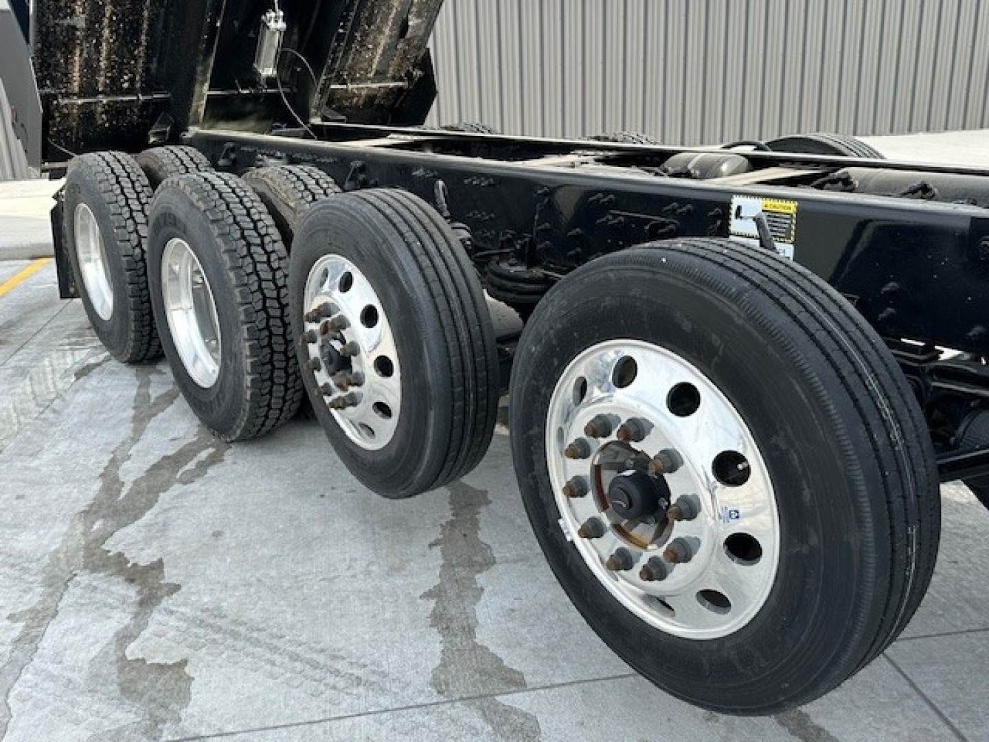 Mack GR104F dump truck chassis showing multiple rear axles with wheels and tires, undercarriage and frame visible.