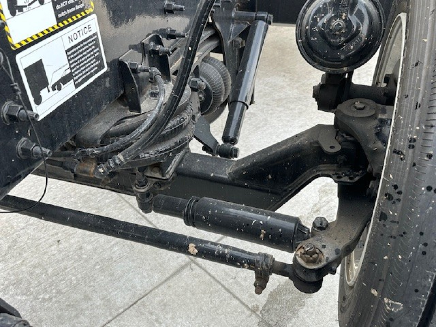 Mack GR104F truck front suspension and hydraulic components with label stickers visible on the chassis.
