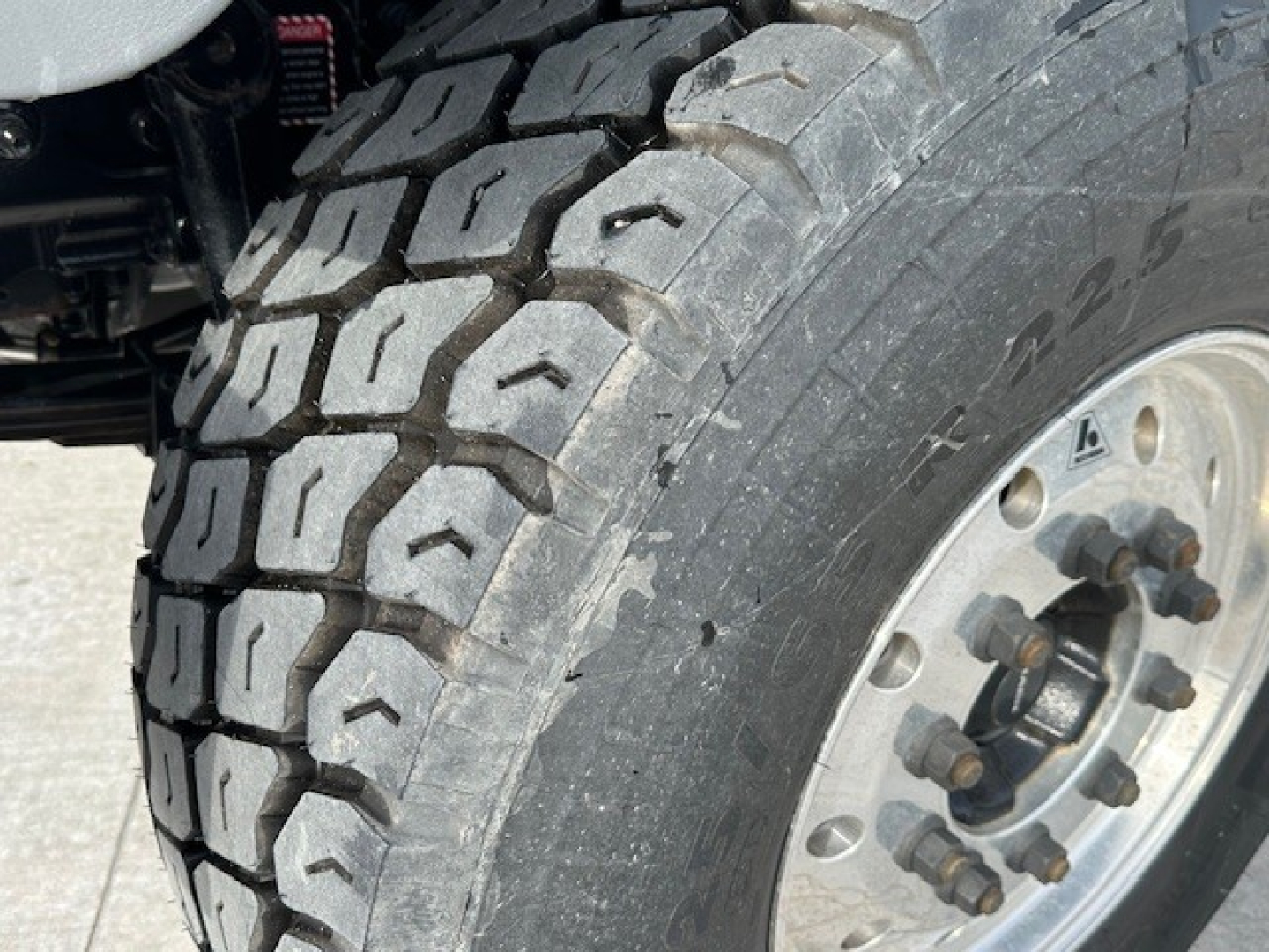 Wheel and tire close-up on a Mack GR104F dump truck showing heavy-duty dual rear tire with tread pattern and industrial steel wheel.
