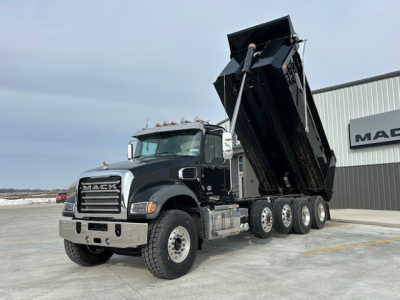 Mack GR104F dump truck with raised dump bed in a dealership yard, front grille and Mack logo visible