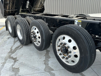 Mack GR104F dump truck chassis showing multiple rear axles with wheels and tires, undercarriage and frame visible.