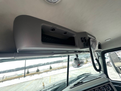 Truck cab interior showing overhead console with storage, microphone cradle, and sun visor area.