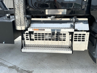 Truck side step and underbody area of a 2025 Mack GR104F dump truck showing metal steps, perforated vents, and hydraulic components.