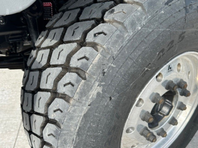 Wheel and tire close-up on a Mack GR104F dump truck showing heavy-duty dual rear tire with tread pattern and industrial steel wheel.