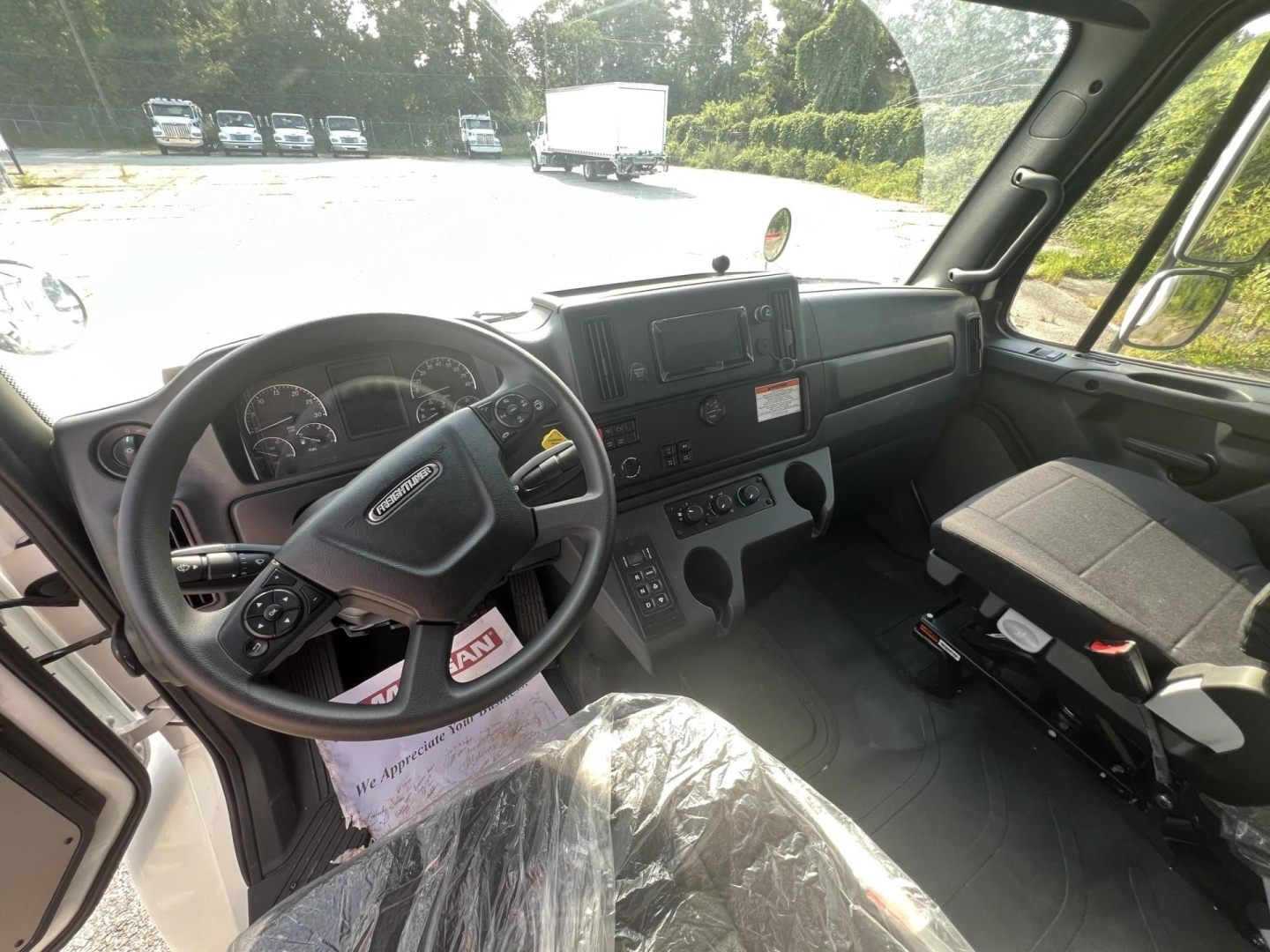 Truck cab interior showing steering wheel, dashboard, and driver seat; visible are instrument panel, center console, control buttons, and passenger seat.