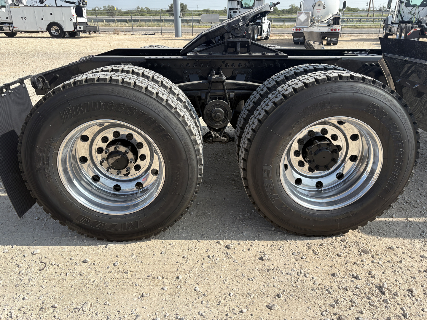 Two large rear dual tires on a Mack GR64FT truck chassis showing Bridgestone tires and chrome wheels.