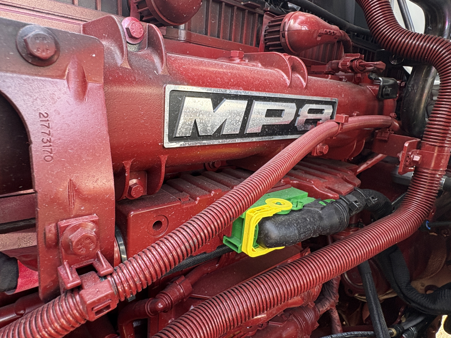 Mack MP engine bay with red components showing MP8 branding and connected wiring harnesses.