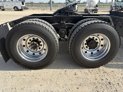 Two large rear dual tires on a Mack GR64FT truck chassis showing Bridgestone tires and chrome wheels.