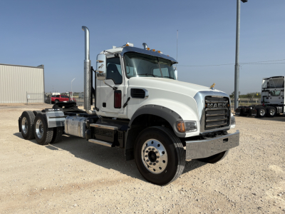 Mack GR64FT truck cab in a trucking lot showing side view with dual rear axles and tall exhaust stack.