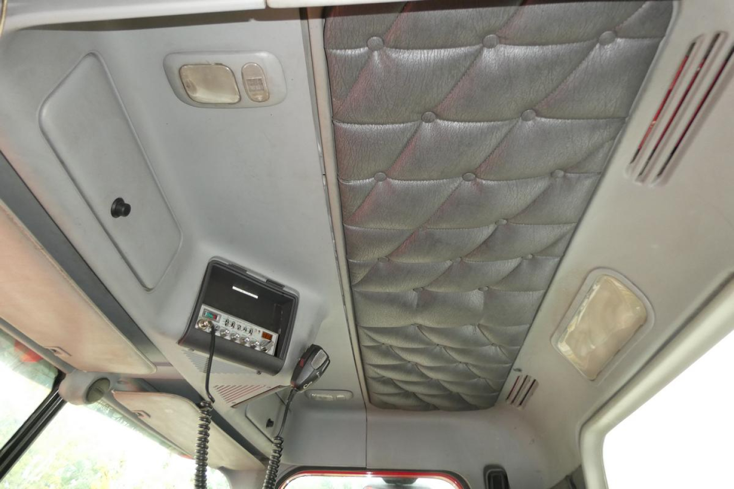 Cab interior of a Freightliner SD122 showing overhead console with mic, control panel, and quilted cab ceiling