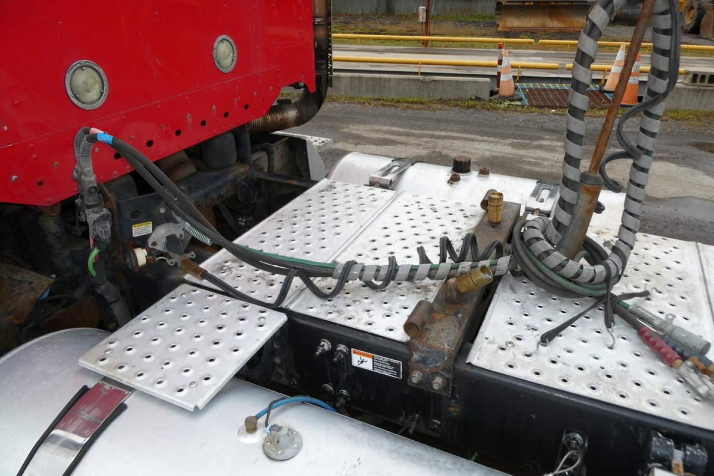 Freightliner SD122 engine bay area showing perforated metal step plates and hydraulic lines near cab and chassis