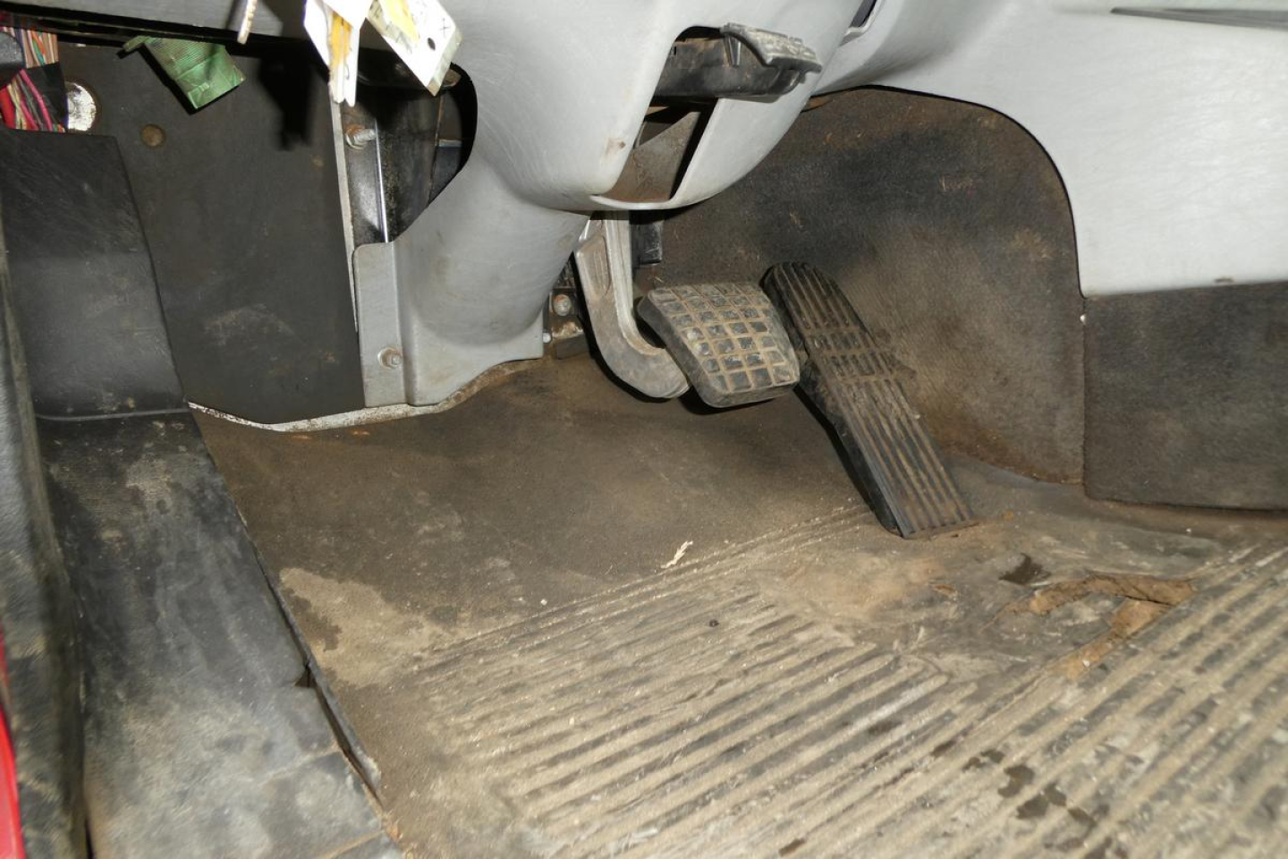 Floor area of a Freightliner SD122 cab with accelerator pedal and brake pedal visible; dirt on floor mat