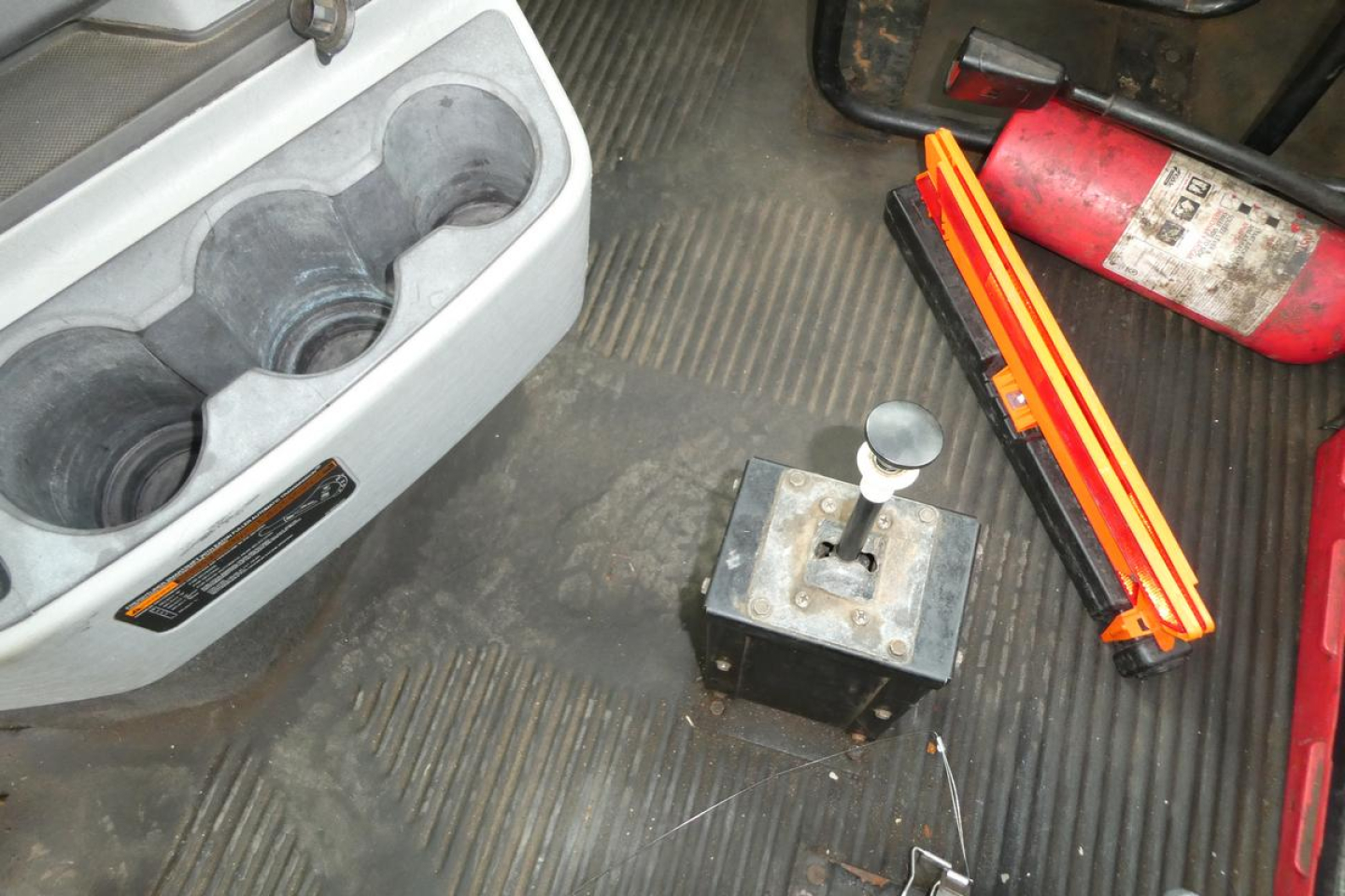 Freightliner SD122 cab interior with gear shifter and accessories including cup holder tray and tools.