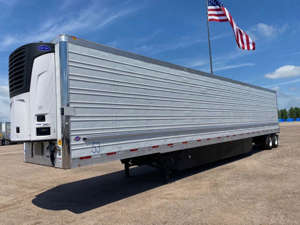 Trailer side view of a 2021 Utility Reefer with a Cryogenic/Life Cooler refrigeration unit at the front left, aluminum ribbed sides, and a white flag in background.