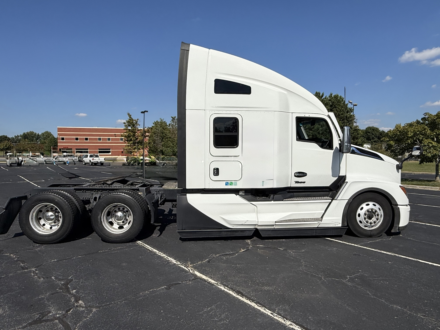 Kenworth T680 tractor side view showing sleeper cab, white exterior, two rear axles, chassis, and wheel details.