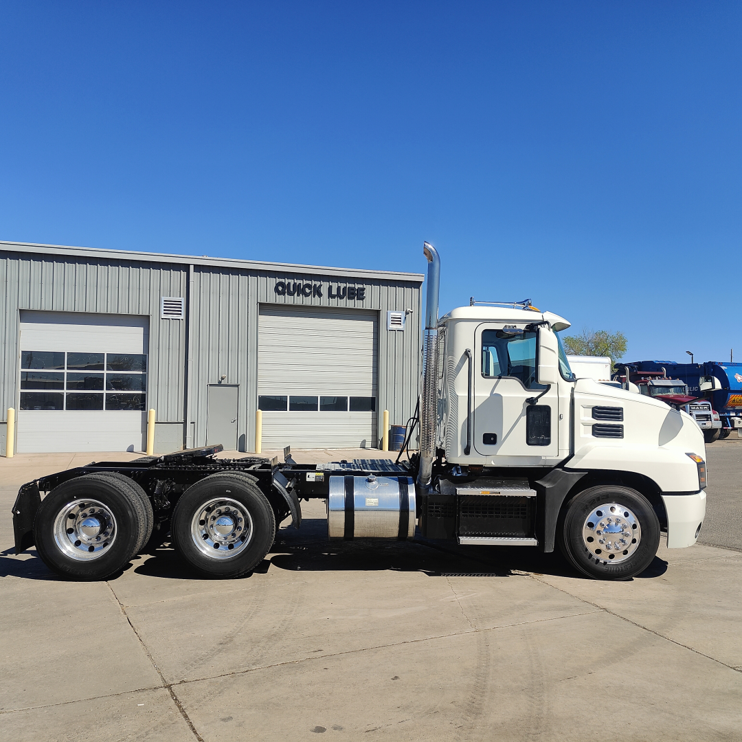 2019 Mack Anthem daycab truck in side view showing chassis, cab, and wheels with a Quick Lube service building in background.
