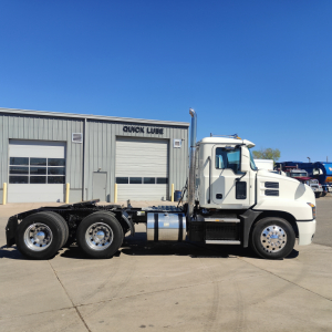 2019 Mack Anthem daycab truck in side view showing chassis, cab, and wheels with a Quick Lube service building in background.
