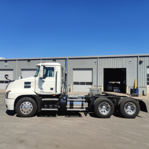 2019 Mack Anthem conventional daycab truck side view showing cab, chassis, and triple rear axles in front of a warehouse.