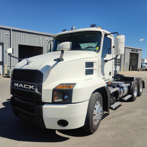 Mack ANTHEM daycab truck in light color showing front grille with MACK emblem and side exhaust, dual rear axles, gas tank, and step rails.