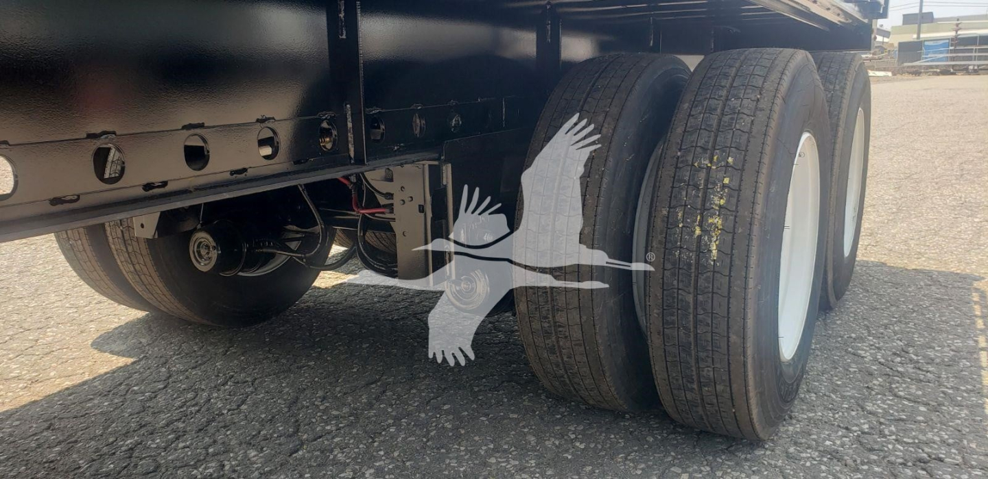 Trailer undercarriage showing rear dual wheels and chassis with white wheel rims and metal frame.