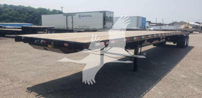 Flatbed trailer with steel air sliding tandem viewed from side showing mirrored reflection and nearby trailers
