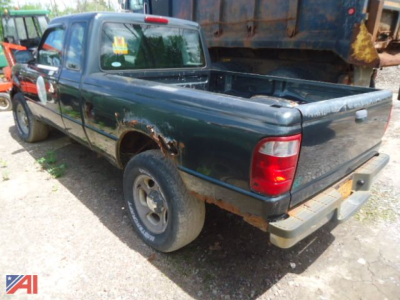 Ford Ranger pickup truck 2005 4x4 in a salvage yard with bed open showing rust and rear bumper; dark green exterior; single cab.