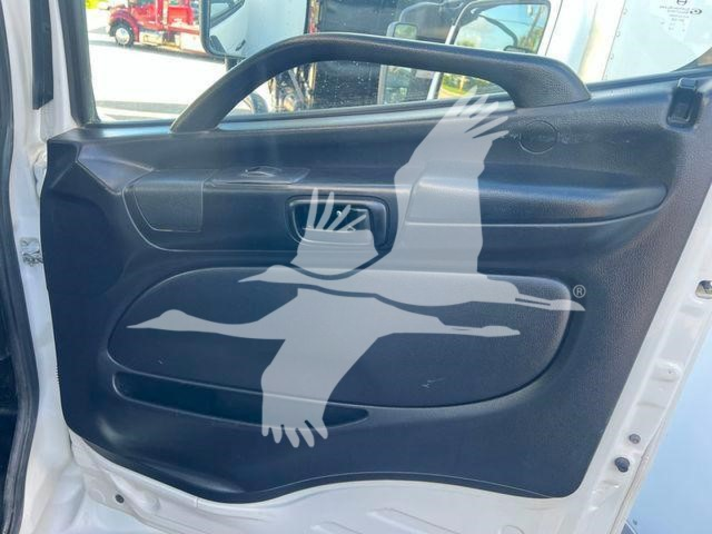 Vehicle interior door panel of a 2019 Hino 338 showing black door trim with handle and window control area.