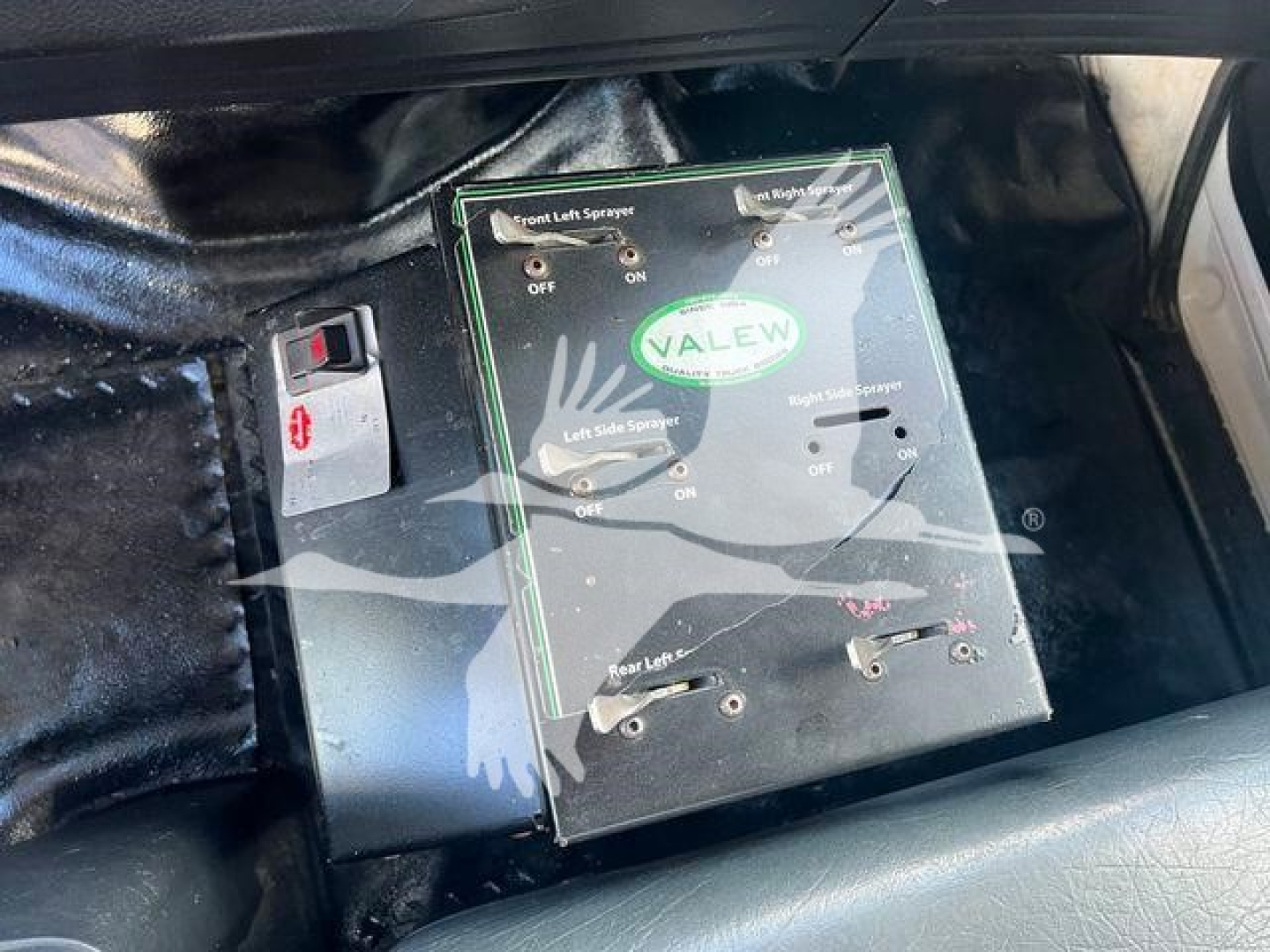 Panel with Valev brand control box labeled Front Left Sprayer and Rear Left Spr., with switches On/Off and levers; part of truck equipment in cab area.