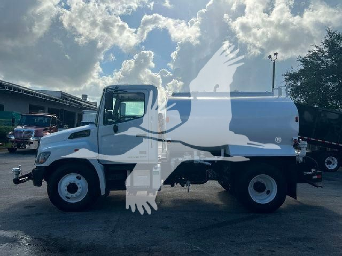 Side view of a white 2019 Hino 338 cab and chassis with twin rear wheels and a water tank body, showing no visible text on the vehicle itself.