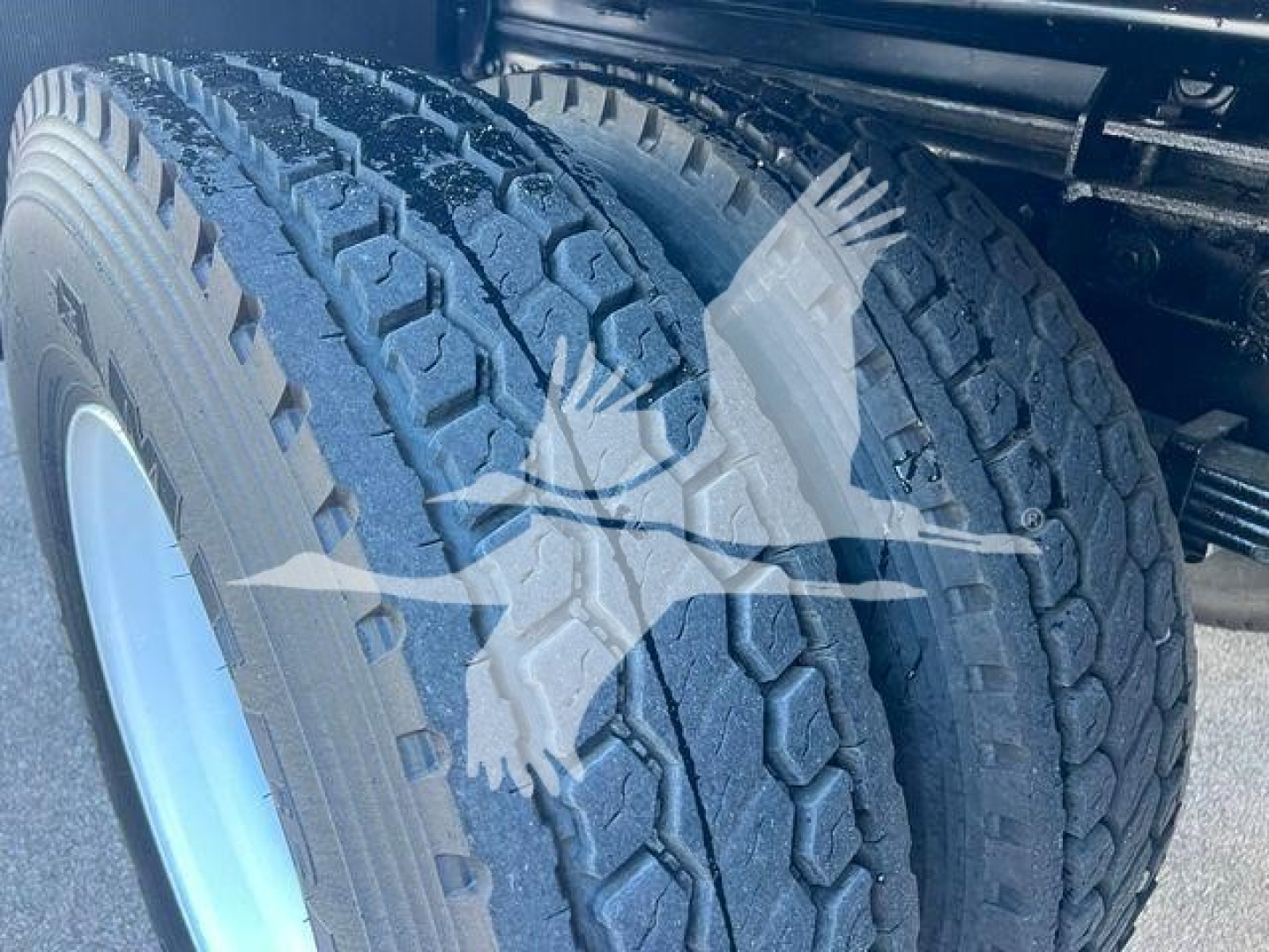 Hino 338 wheel/tire area showing heavy-duty dual rear tires and wheel well, no visible text other than the tread pattern.