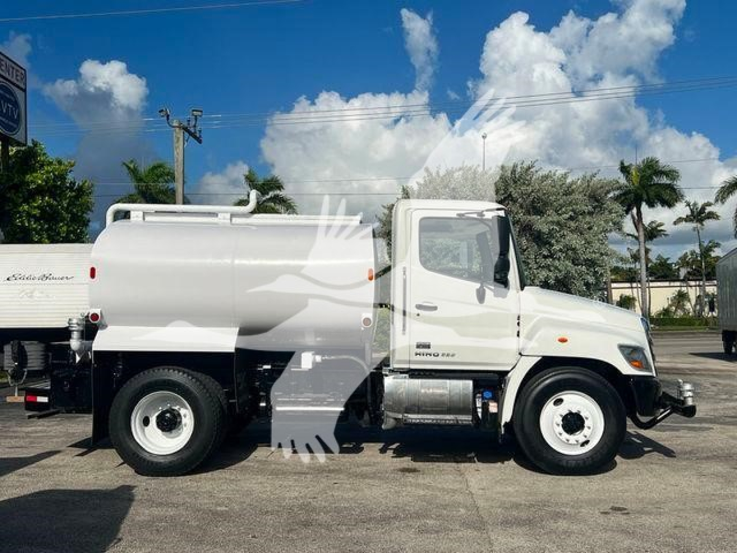 Hino 338 vacuum truck side view showing white tank and cab with dual rear wheels and chrome fuel tank.
