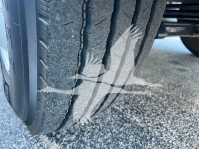 Tire tread close-up on vehicle showing rear dual tires of a 2019 Hino 338 with gravel surface.