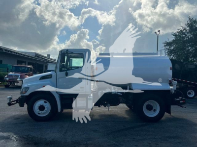 Side view of a white 2019 Hino 338 cab and chassis with twin rear wheels and a water tank body, showing no visible text on the vehicle itself.