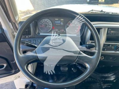 Interior view of a 2019 Hino 338 steering wheel and dashboard. Visible gauges include speedometer and tachometer, steering wheel with center emblem, and climate controls.