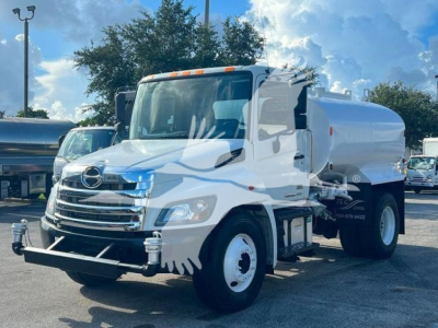 Hino 338 medium-duty tanker truck in a lot showing front-right view with chrome grille and white tank.