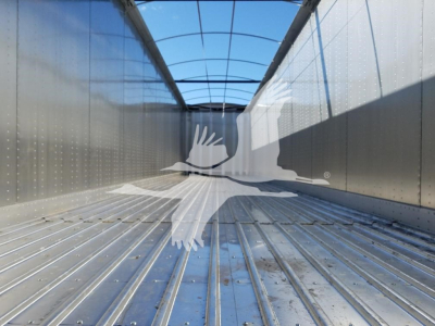 Trailer interior view of an open top Dorsey trailer showing metal ribbed floor and sidewalls, with a transparent curved roof at the top.