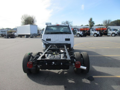 Truck chassis cab from rear showing frame rails, dual rear wheels, and taillights in a parking lot.
