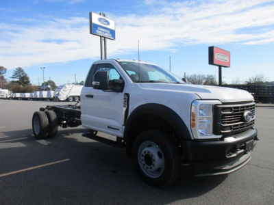 2026 Ford F-450 Cab and Chassis truck in dealership lot, side/front view showing Ford grille, white cab, no bed, dual rear wheels, dealership signage in background.