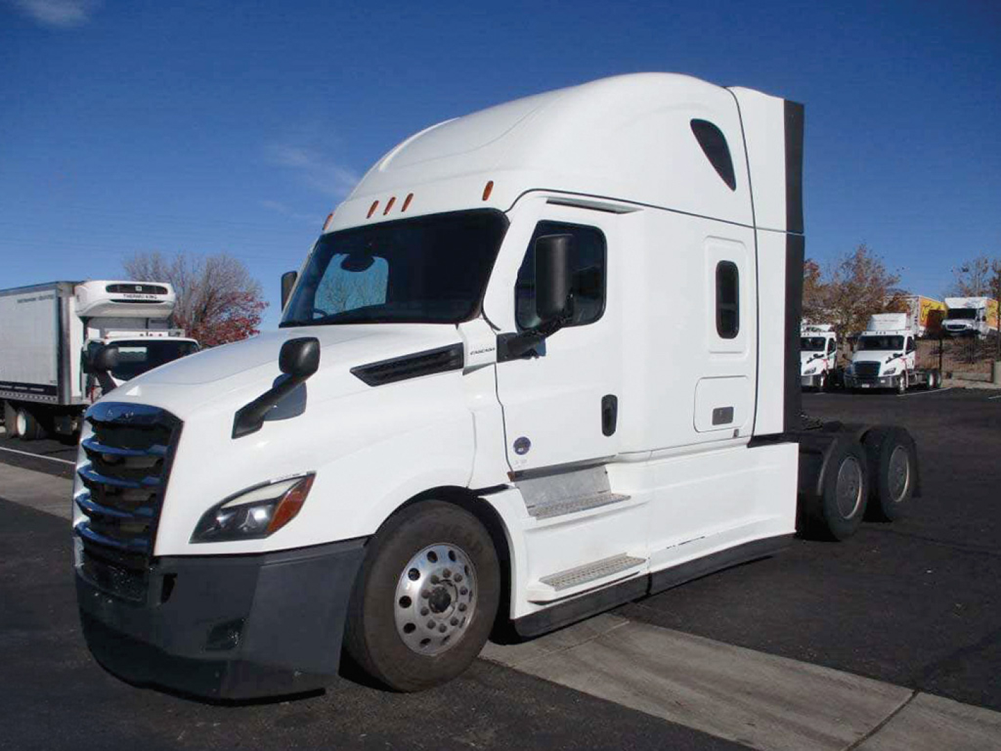 Truck cab side view showing Freightliner Cascadia exterior with aerodynamic mirrors, grille, and dual rear axles; no legible sticker text visible.