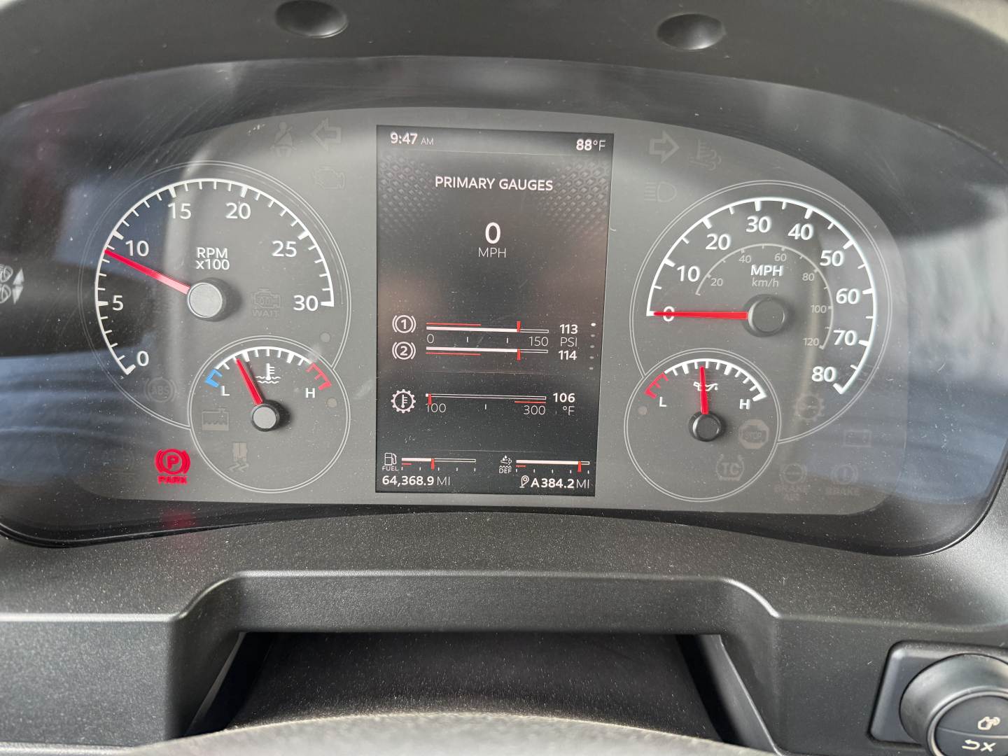 Dashboard display showing primary gauges for RPM and speed with central digital screen; analog speedometer and tachometer on either side; various warning indicators and vehicle stats visible.