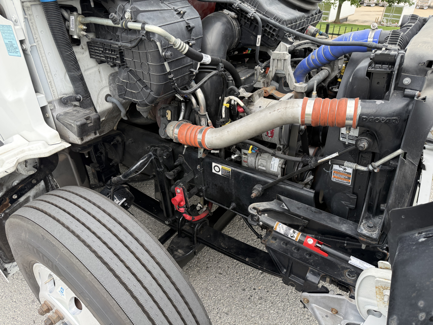 Kenworth T380 engine bay showing coolant hoses, air intake, and wiring with label stickers visible.