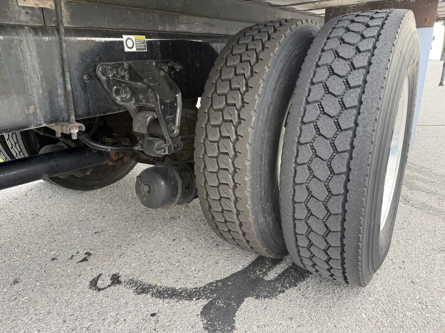Kenworth T380 rear dual tires and chassis showing wheel area and undercarriage, with oil/fluid trace on pavement.