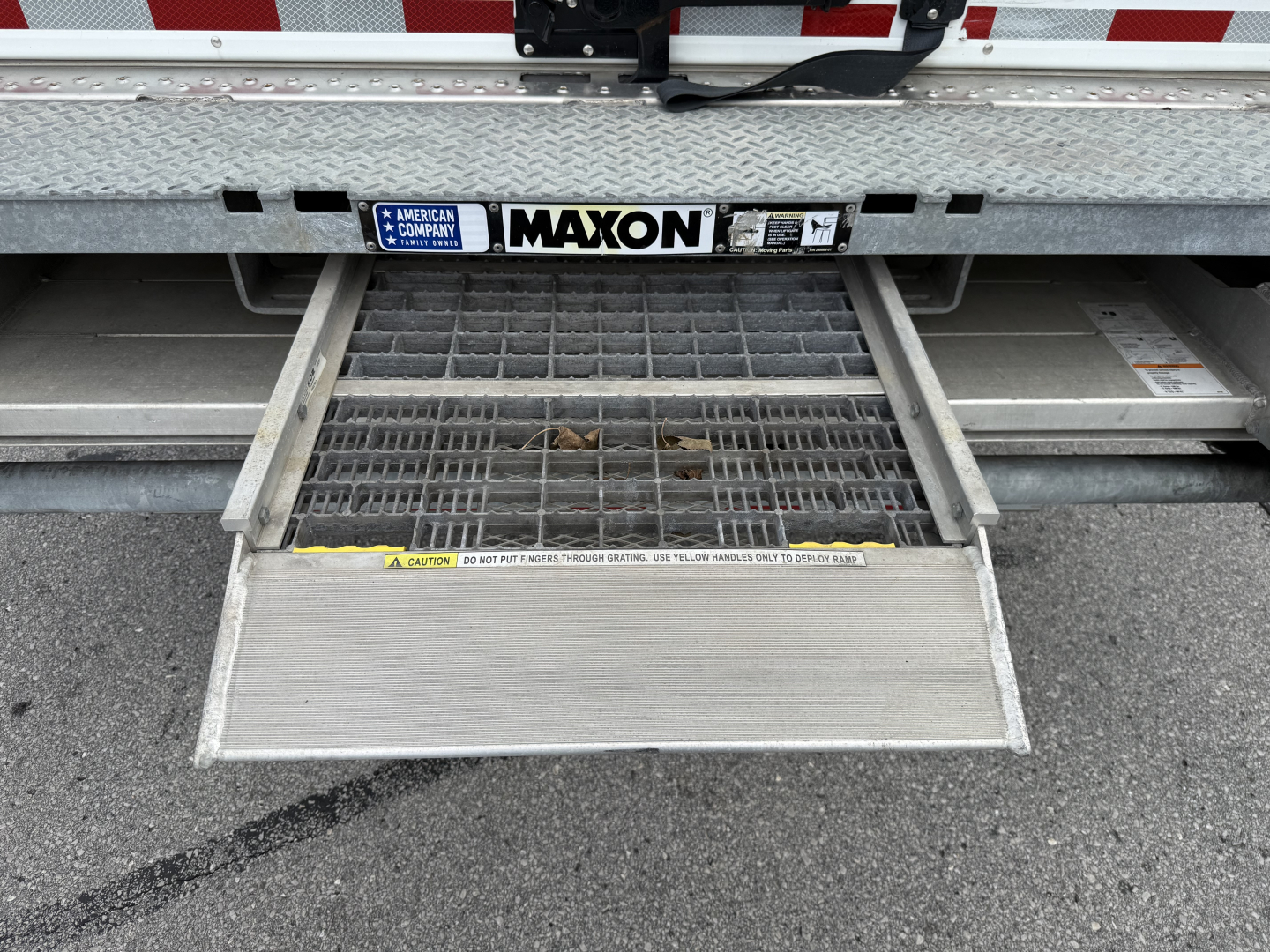 Truck rear showing a cargo lift/step with MAXON label and rear bumper, generic Maxon gate.