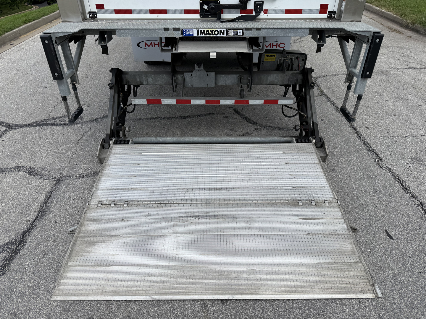 Truck rear showing hydraulic liftgate folded up, with platform extended slightly, undercarriage and bumper visible.