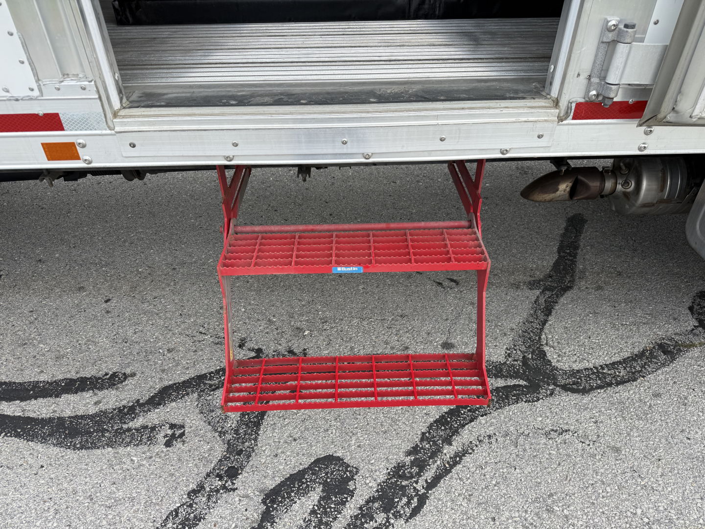 Kenworth T380 refrigerated truck with red fold-out steps under rear doors and cargo area visible.