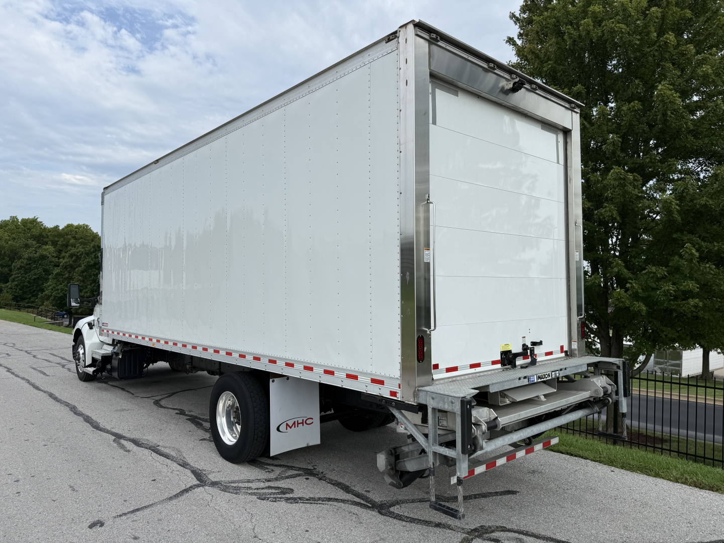 Kenworth T380 refrigerated truck rear and side view showing box trailer and liftgate, white exterior, bumper, and rear hinges.
