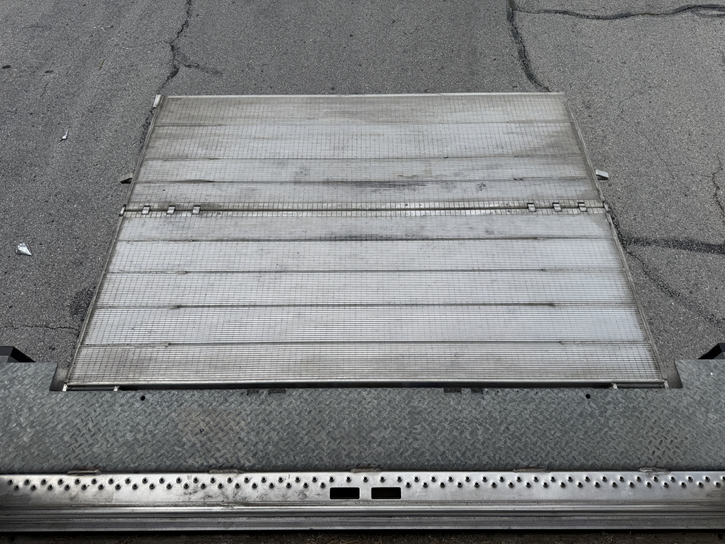 Truck alloy ramp with perforated step edges and track grooves visible; no readable labels or text on the ramp surface.