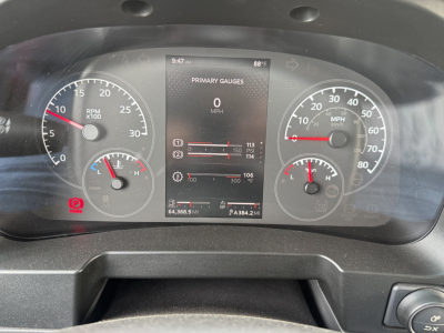 Dashboard display showing primary gauges for RPM and speed with central digital screen; analog speedometer and tachometer on either side; various warning indicators and vehicle stats visible.